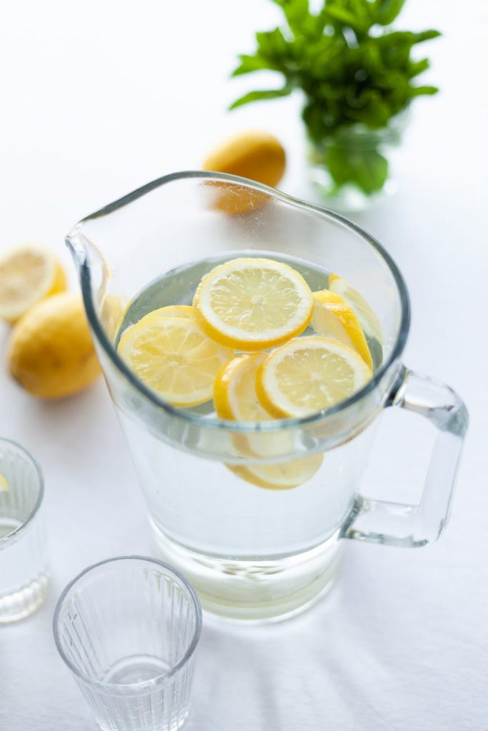 clear glass pitcher filled with clear liquid and slices of lemon água aromatizada
